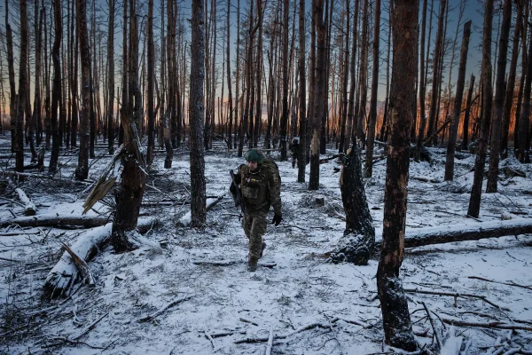 A Ukrainian soldier retreats through a snowy forest after firing a propelled grenade.